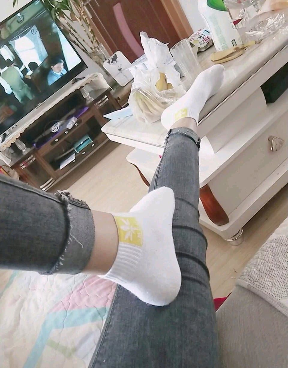 Home snapshot of feet on a couch, stockings rolled down and a teasing glimpse of bare toes