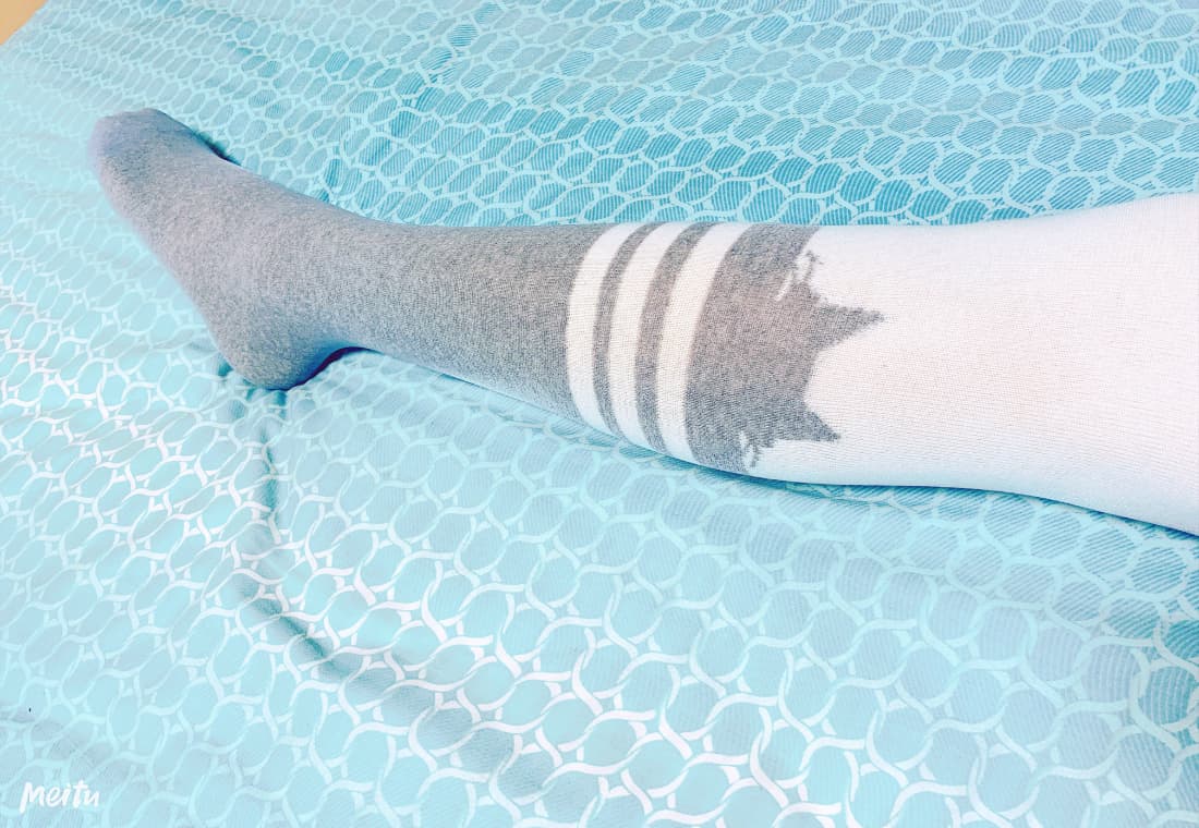 Close-up of bare feet pressed against rain-soaked window, stockings bunched around ankles, soft lighting and wet reflections