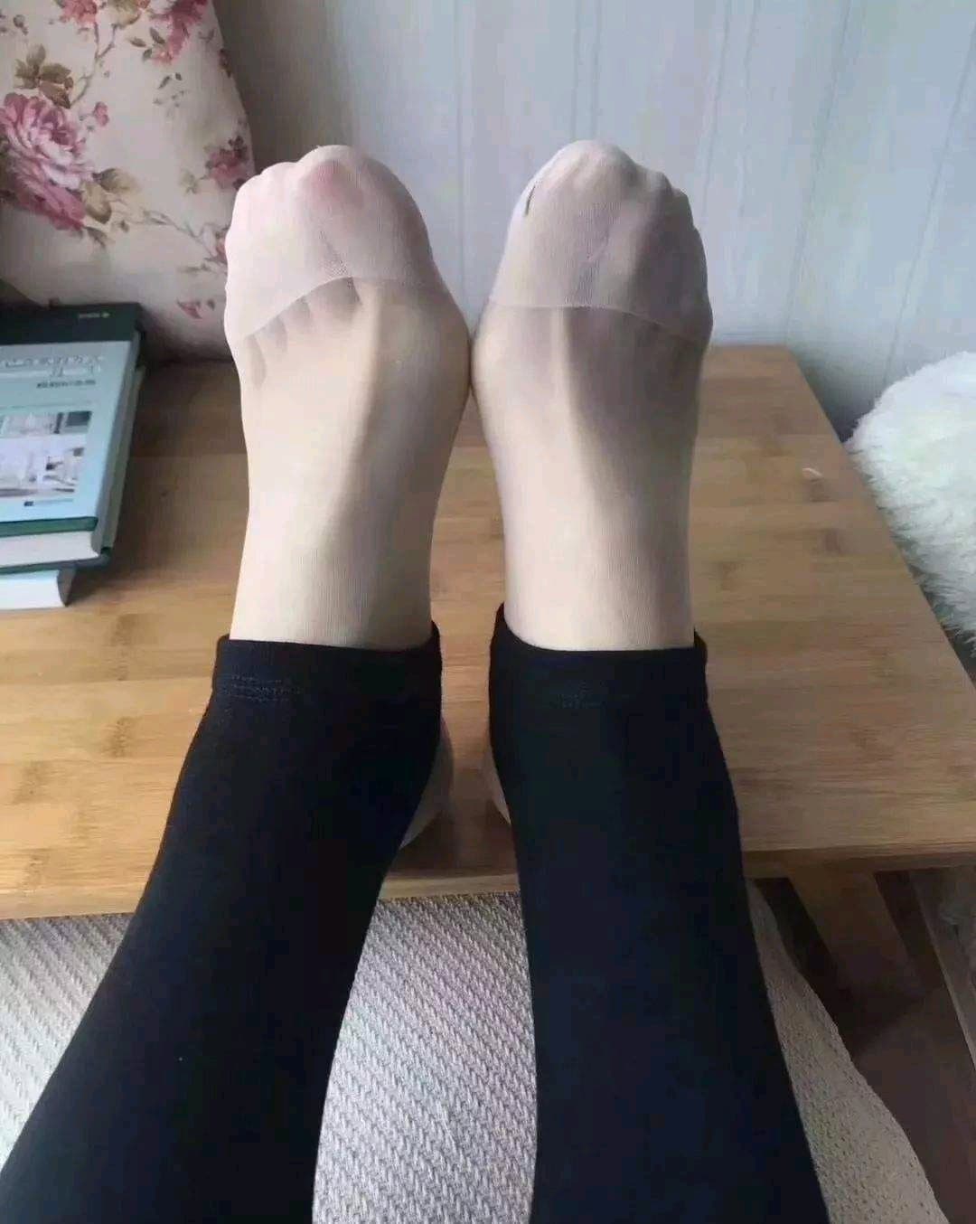 Relaxed bare feet resting on couch, toes slightly curled with cozy cotton socks nearby