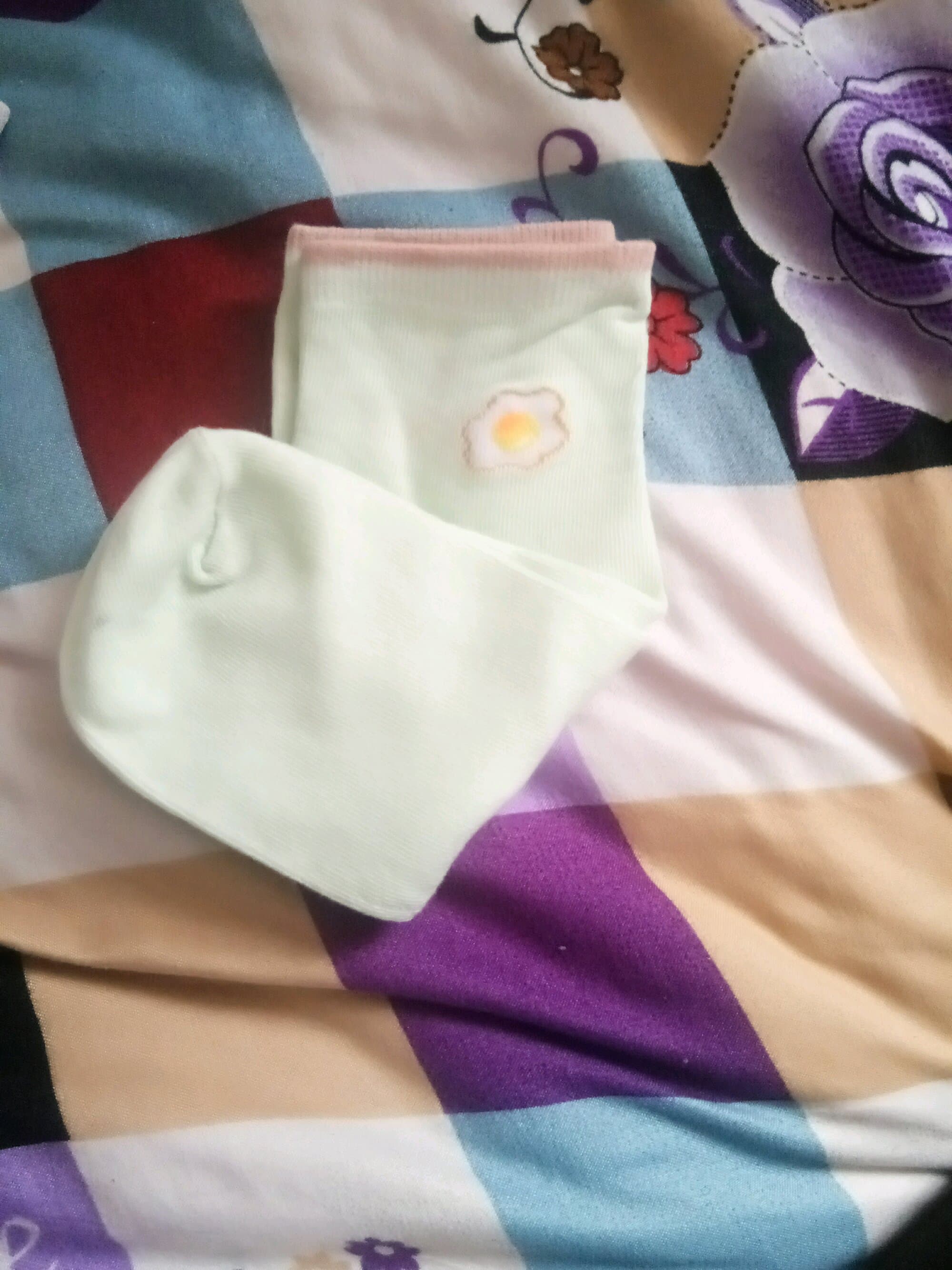 Casual close-up of feet in mixed hosiery, one sock rolled down and a stocking seam accenting the calf curve