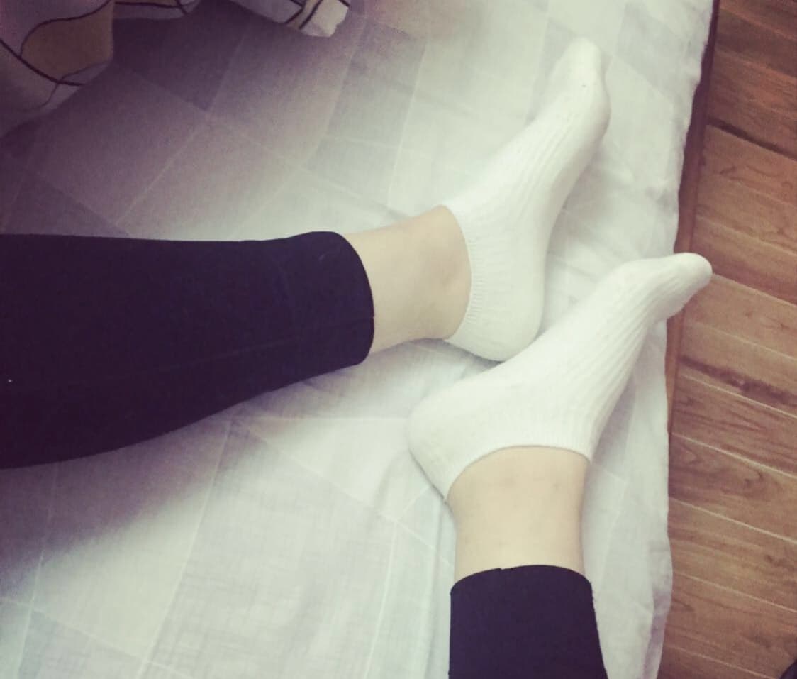 Intimate portrait of feet resting together, one foot in a cozy cotton sock and the other bare, toes gently touching