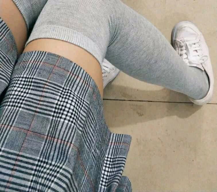 Smiling model wearing slightly worn cotton socks, sitting casually with ankles crossed and toes peeking out playfully