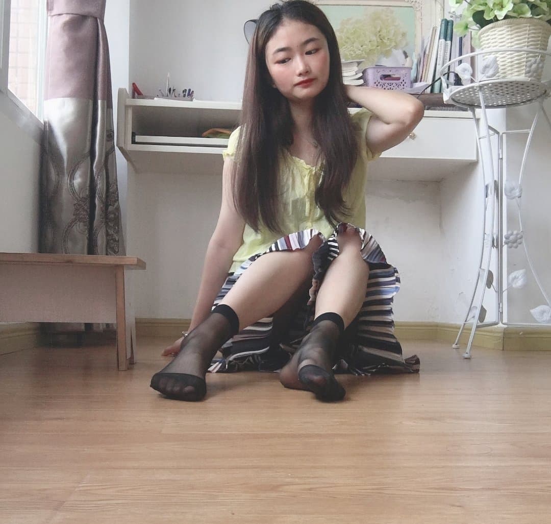Petite woman reclining, bare feet arched toward camera, soft light highlighting skin texture and delicate toes
