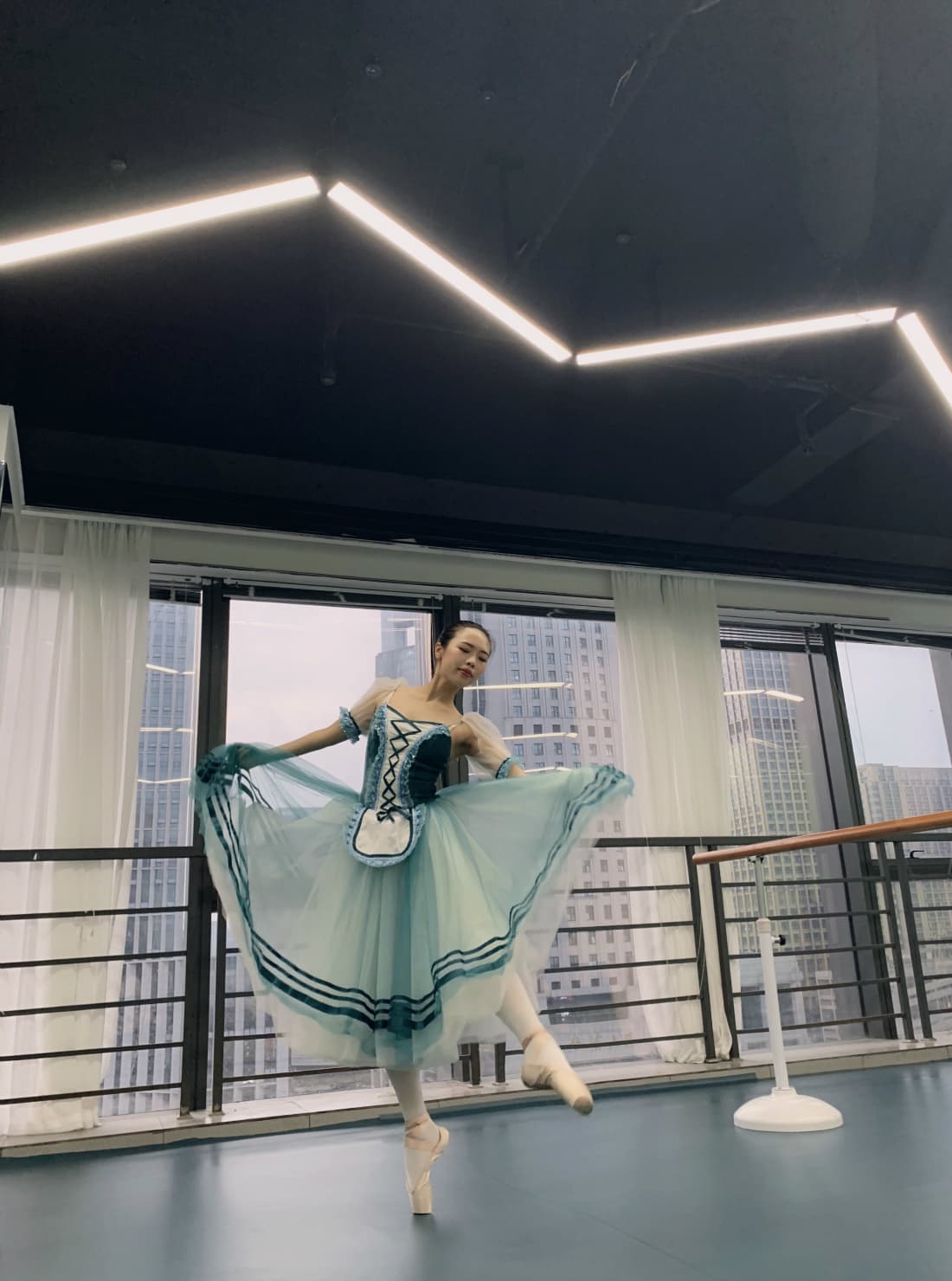 Adult ballet dancer stretching, tights hugging supple arches, close view of pointed foot and delicate ankle lines.