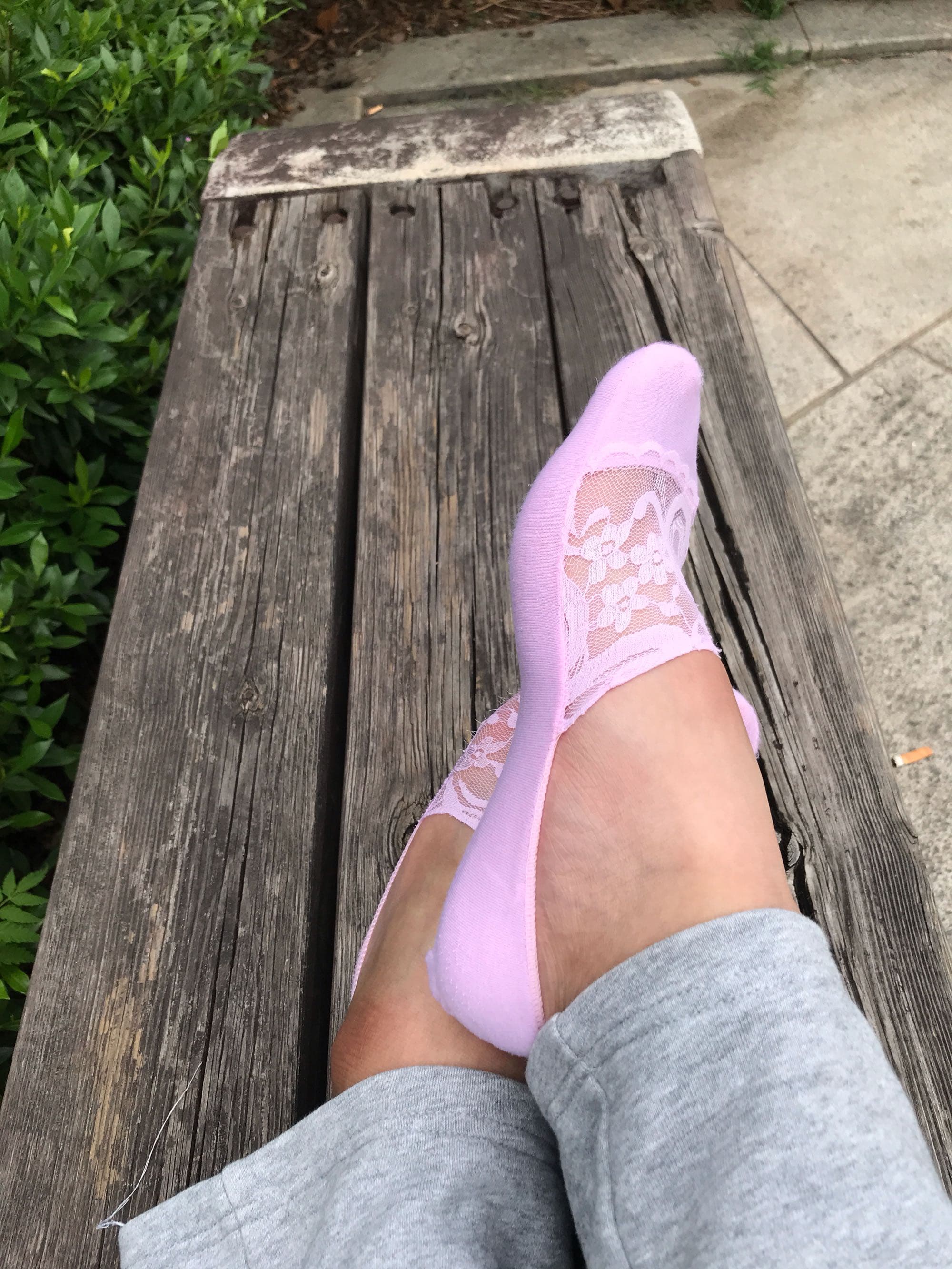 Close-up of adult feet in pink lace boat socks, delicate scalloped edges visible, toes peeking and arch gently flexed.