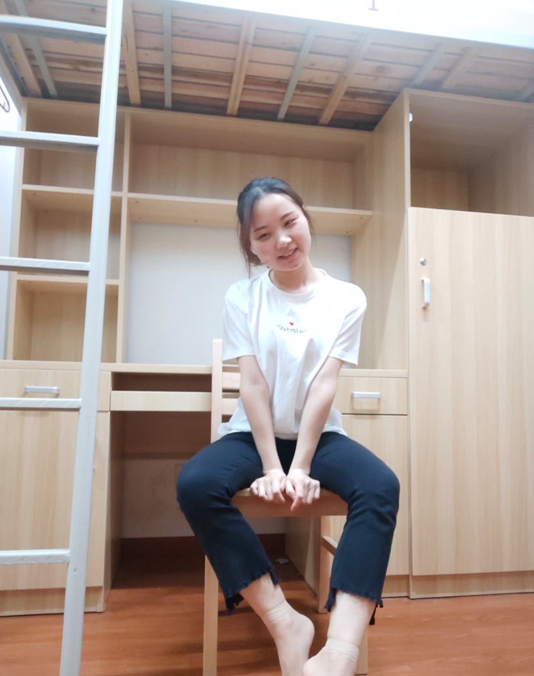 Cozy dorm corner with bare feet peeking from under blanket, used cotton socks folded nearby on a chair.