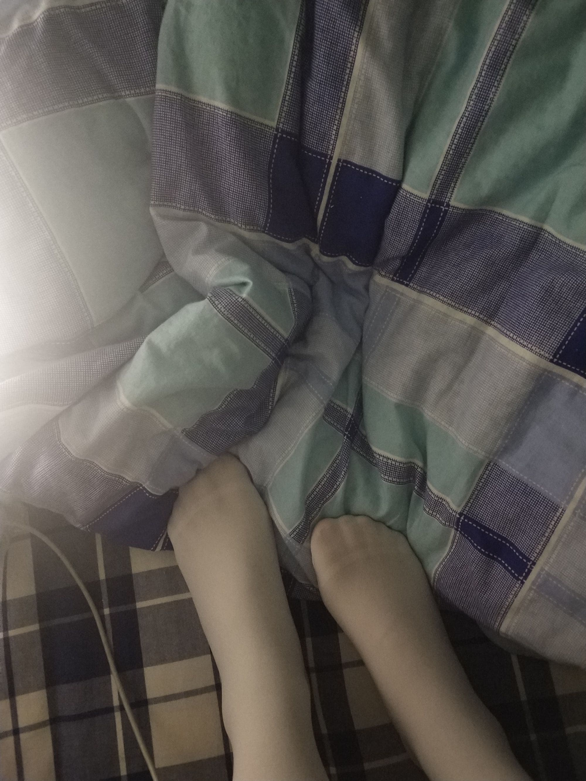 Playful bare soles flexing, one foot half-pulled from a cotton sock while laughter lingers in the room.