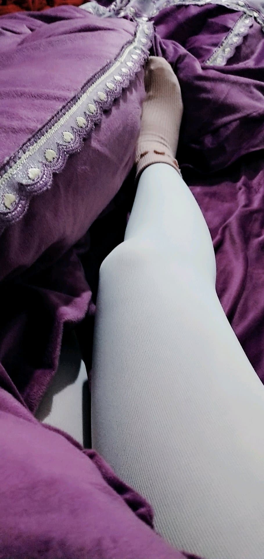 A quiet scene with crossed stockinged legs, toes tapping softly while the person maintains a secretive, playful silence.