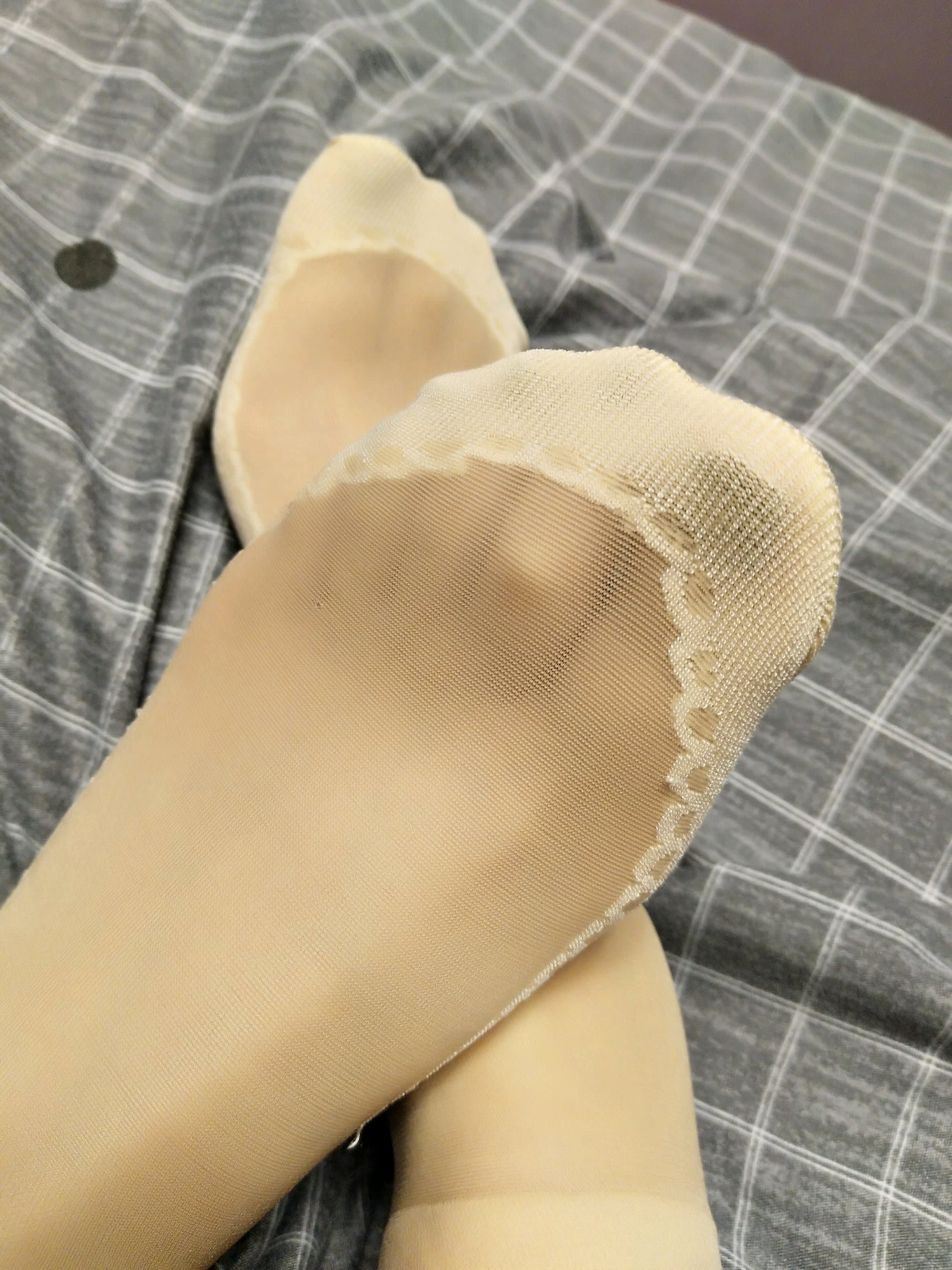 Close-up of feet wearing flowered cotton socks, petal patterns visible, soft creases suggesting warm, worn comfort