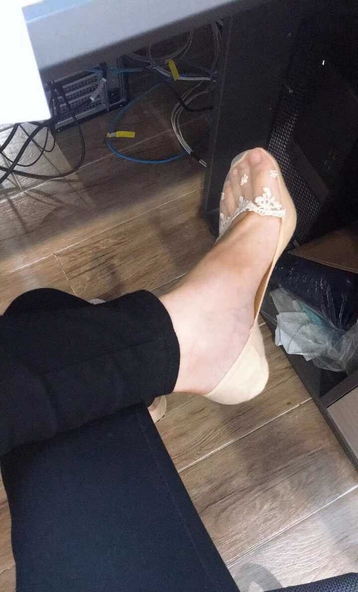 Relaxed shot of ankles wrapped in soft cotton socks with a rolled cuff, toes slightly curled in comfortable pose