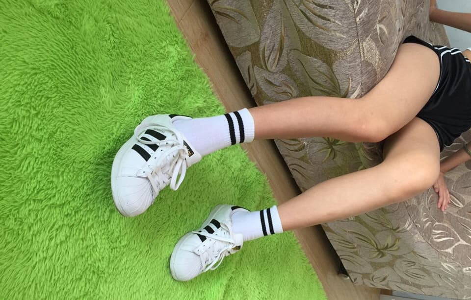 Close-up of bare feet slipping out of work shoes, stocking edges rolled, toes peeking, soft evening light caressing skin