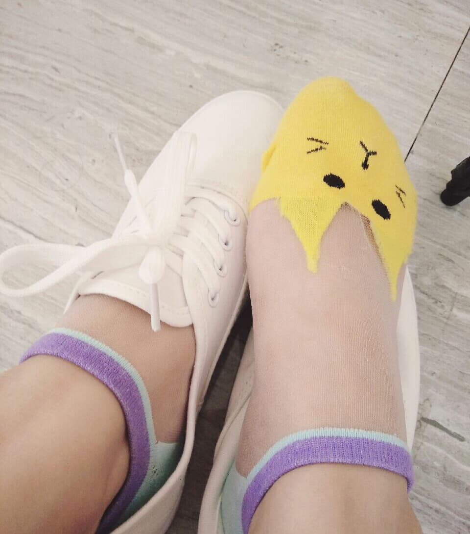 Foot in clear, glass-like shoe with cotton sock visible beneath, toes pressed against glossy surface