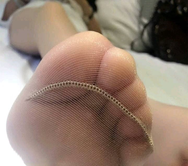 Silk stocking slid down to reveal a bare ankle and soft toes, lit by warm, intimate lighting