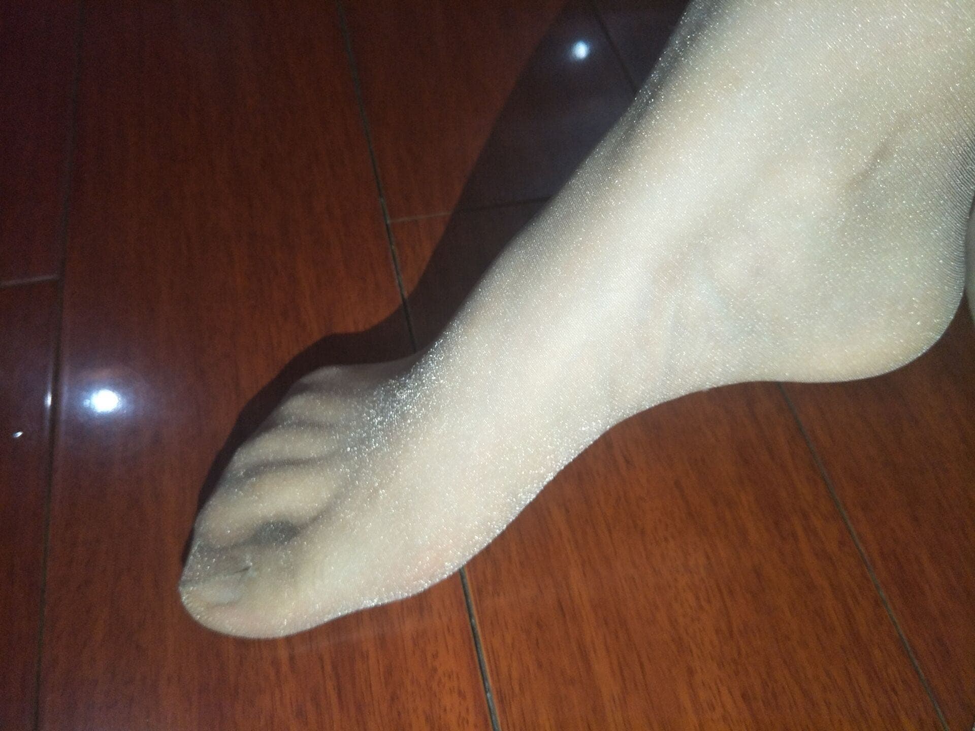 Pair of feet, one in thick cotton socks and the other in glossy stockings, side-by-side comparison of textures