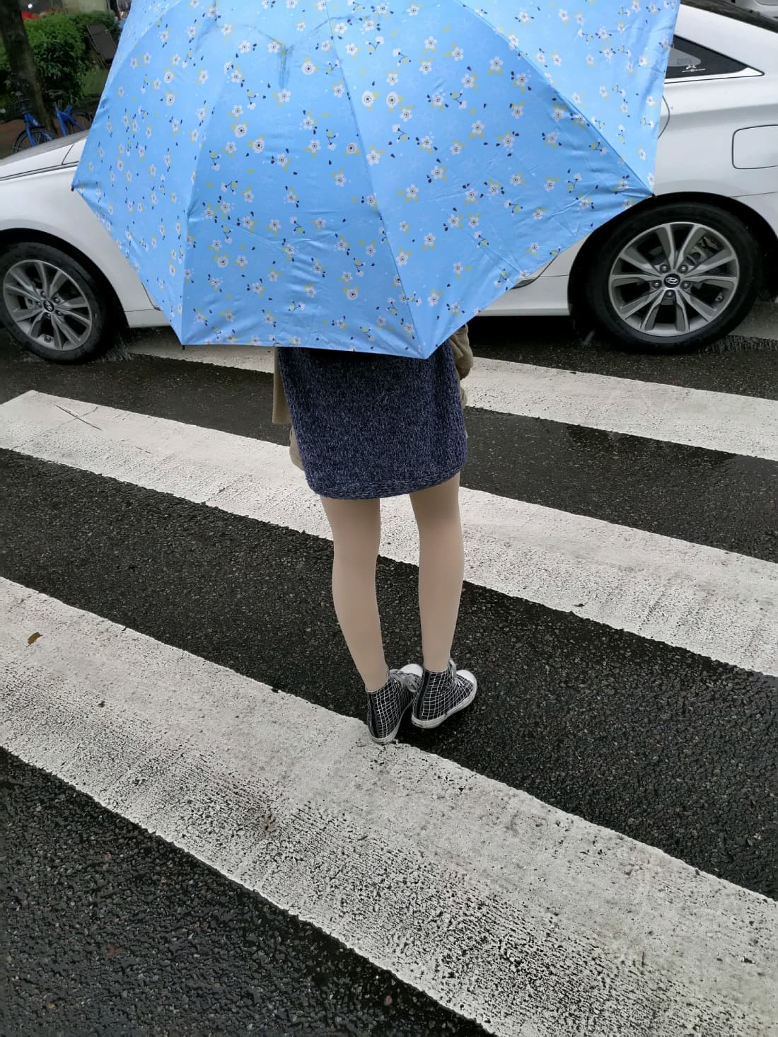 Feet in sheer stockings stepping across zebra crossing, toes visible, asphalt textures contrasting soft nylon