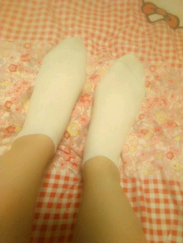 Worn cotton socks half-pulled from bare feet, cozy texture and gentle wrinkles framing soft arches and toes