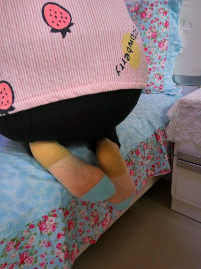 A wife leaning on a bed as she peels down a stocking, exposing a soft sole and delicate ankle curve.