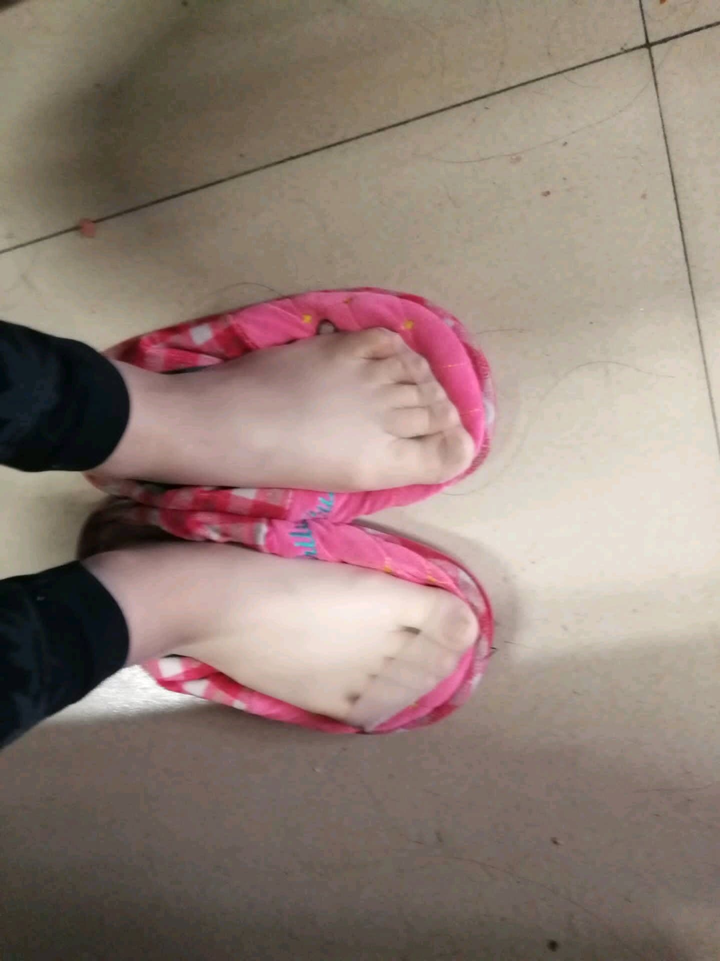 Close-up of bare feet with glossy nylon stockings, toes peeking from delicate lace trim, warm bedroom glow.