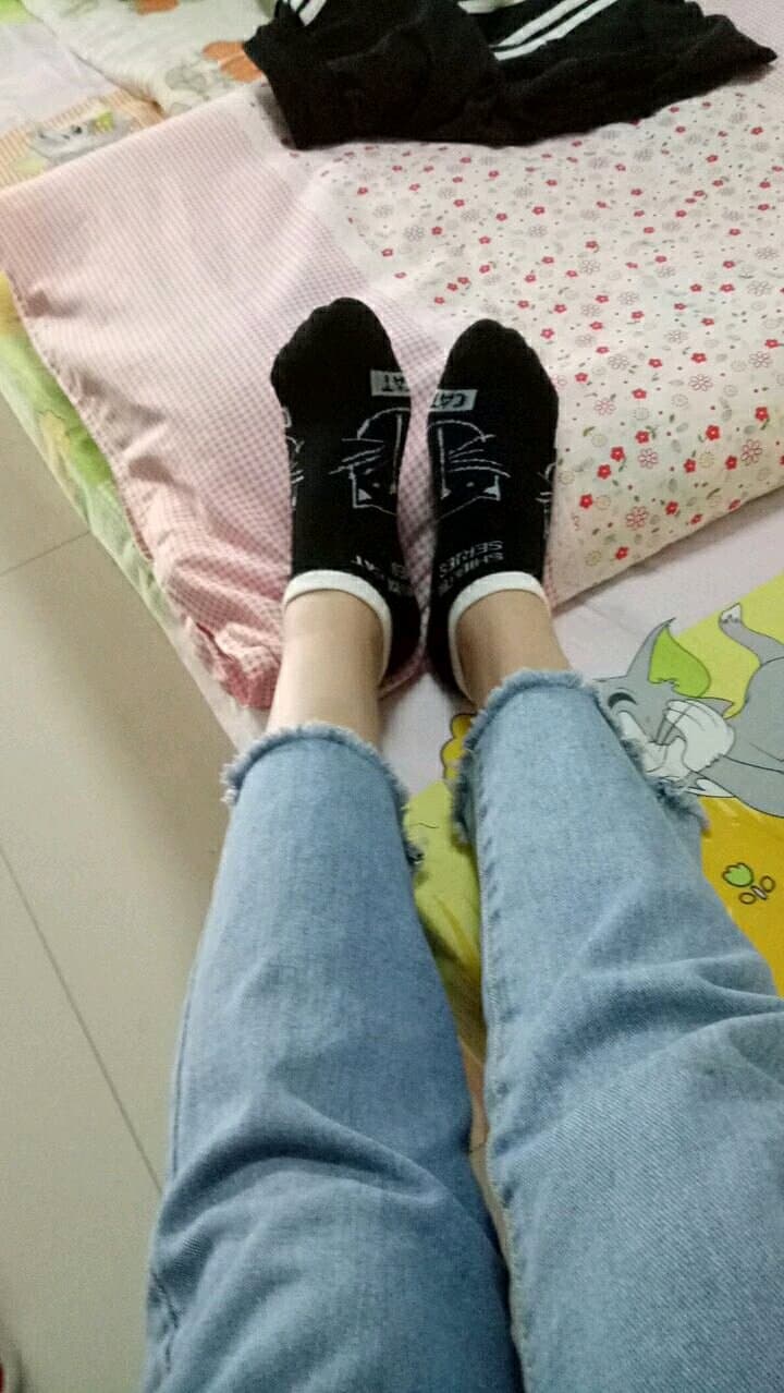 After-hours classroom scene with a woman in stockings dangling her bare feet over a desk edge