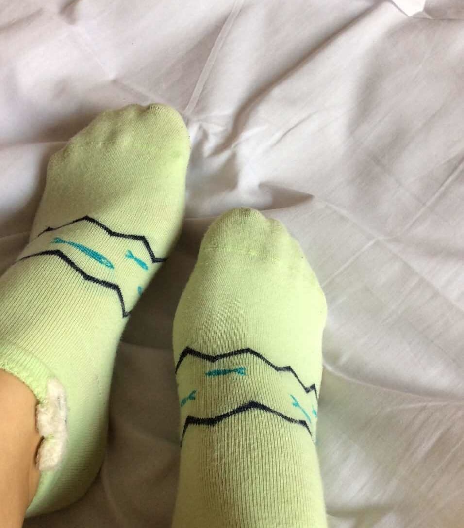 Two feet side-by-side, one bare and one in sheer stockings, intimate proximity and playful composition