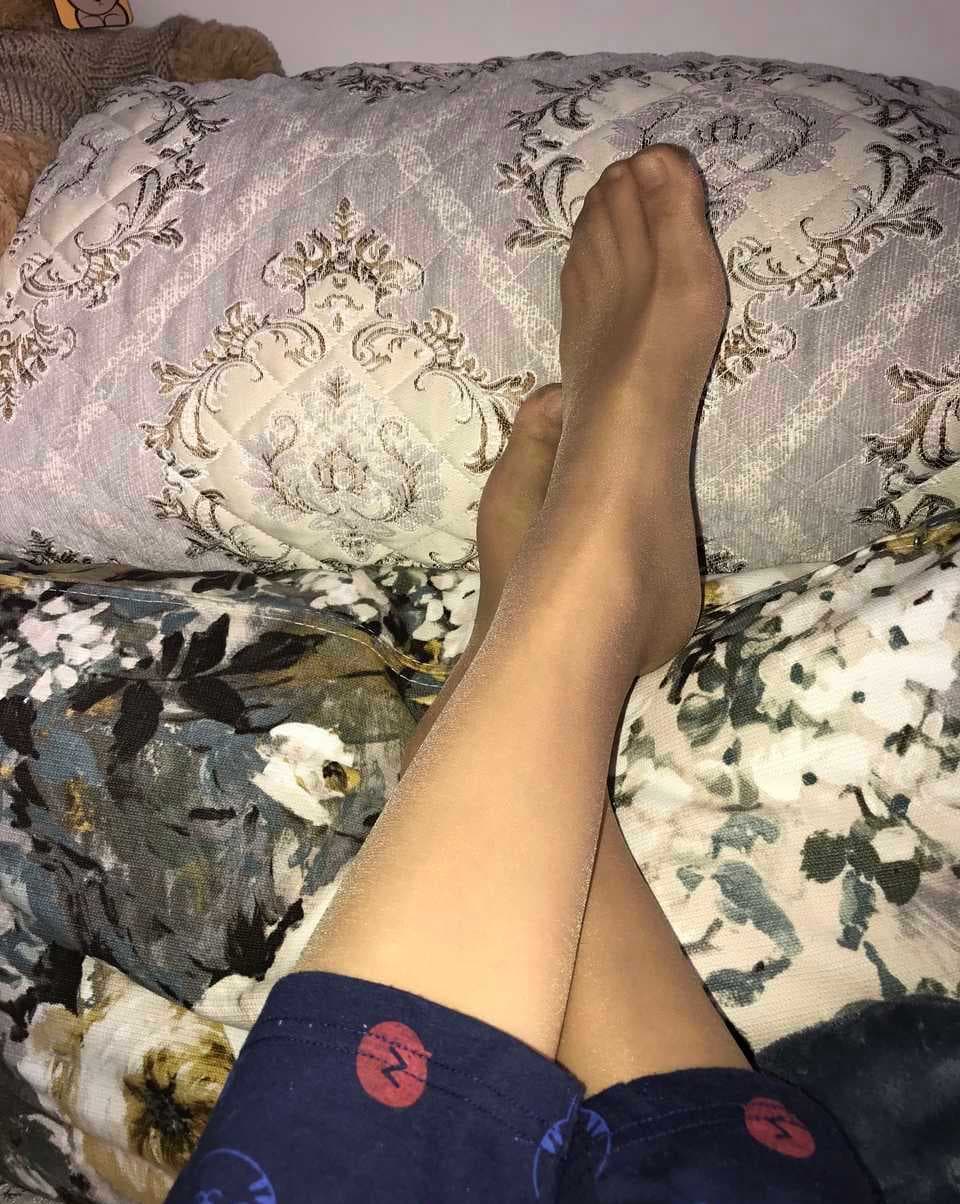 Intimate portrait of silky feet in sheer stockings, highlighting arches, heels, and nylon sheen in warm lighting