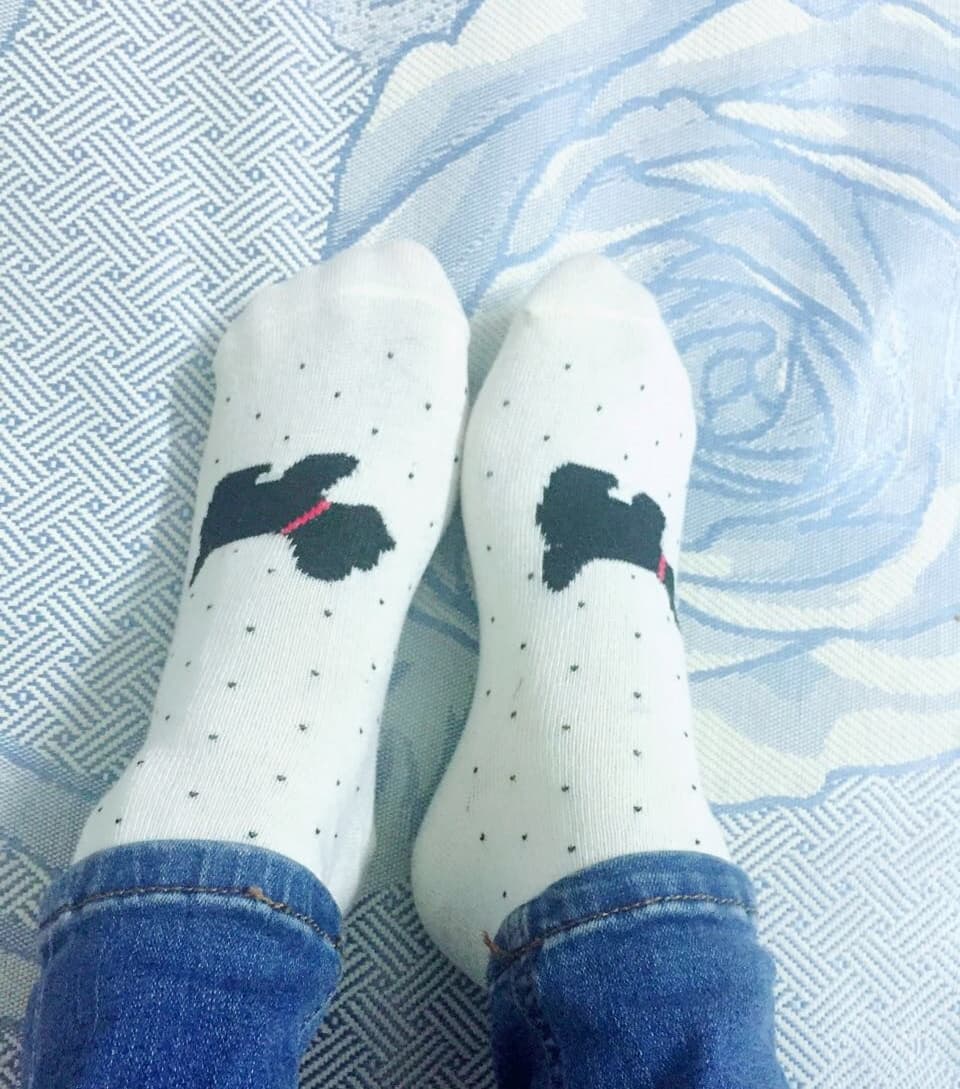 Cuffed blue jeans revealing worn cotton socks and an exposed ankle, toes subtly curling at the hem.