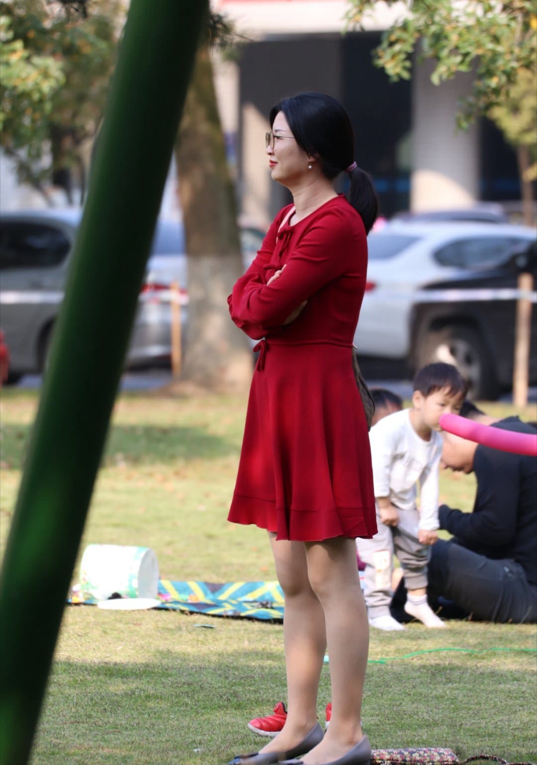 Sunlit park bench close-up of naked toes peeking from sheer stockings, grass visible beneath feet.