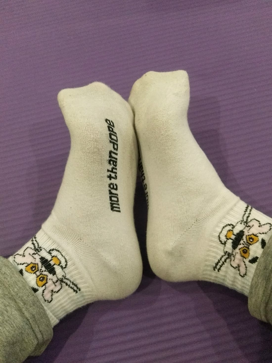 Worn cotton socks slouched around ankles, soft texture visible as toes peek out playfully