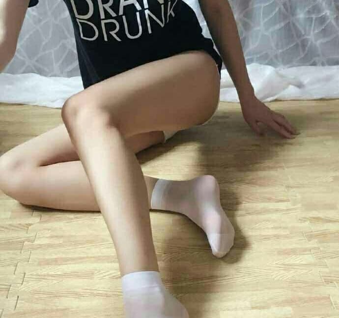 Petite figure reclining with bare feet exposed, toes slightly curled and sheer ankle stockings slipping down