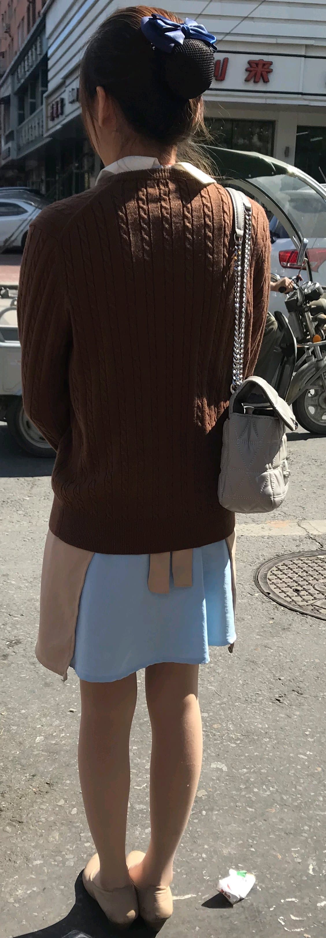 Candid shot of a socked ankle and bare heel on city pavement, juxtaposing soft skin with urban texture