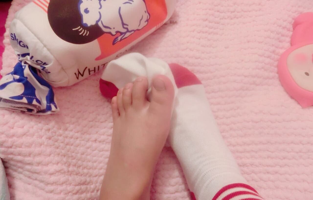 Red satin ribbon wrapped around the ankle above a partially exposed foot, creating a bold, intimate contrast