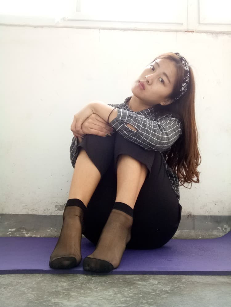 Foot half-clad in glossy nylon with exposed toes, highlighting the tactile contrast between fabric and skin