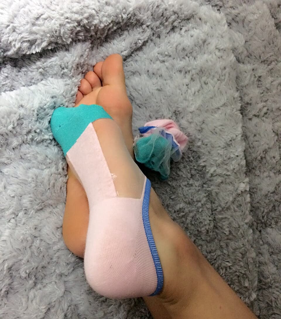 Playful adult posing with bare toes peeking out and stockings rolled at the ankles, coy smile hinted