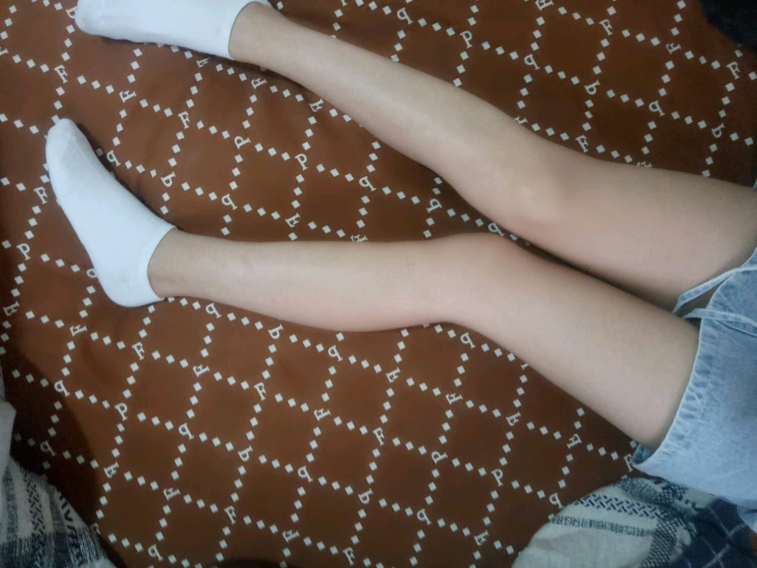 Close-up of bare Asian feet on satin sheet, toes slightly curled in warm evening light