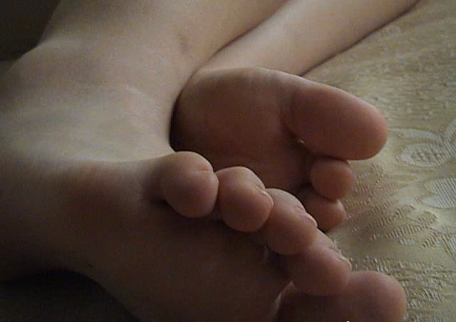 Nervous model adjusting stockings, close-up on trembling toes and delicate ankle with soft, intimate lighting