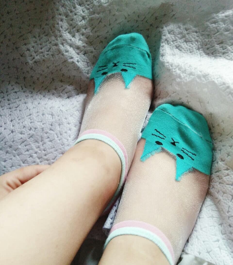 Glossy green-tinted stockings hugging bare toes, close-up on nylon texture and glossy sheen