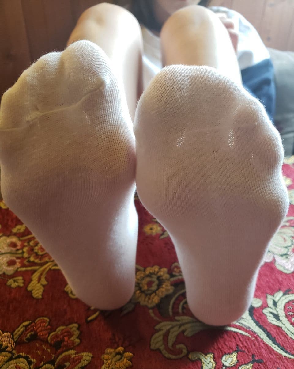 Warm close-up of foot wrapped in soft cotton sock, fabric hugging arch and showing natural texture