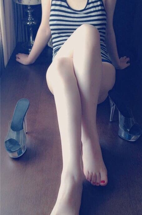 Elegant figure wearing stockings, feet poised with arched soles and delicate toes visible, suggesting confident sensuality and refined allure