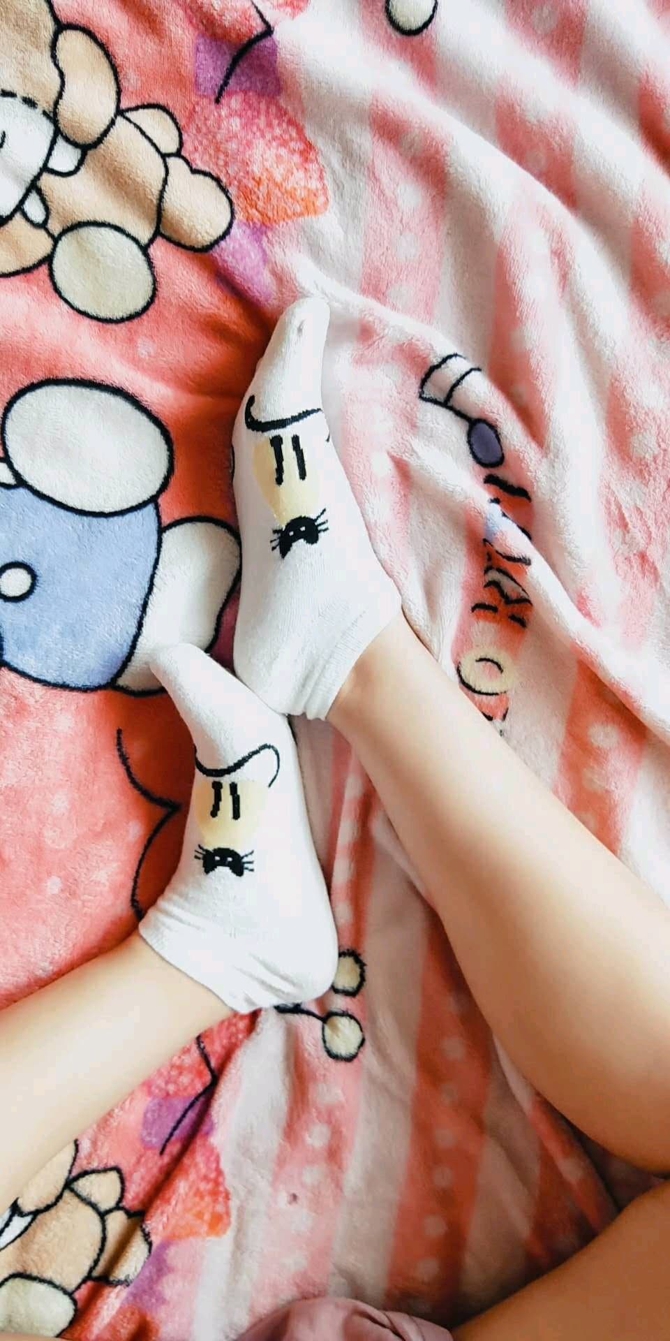 Casual feet in slightly rumpled socks resting on a couch, textures and slight sheen suggesting lived-in, intimate comfort