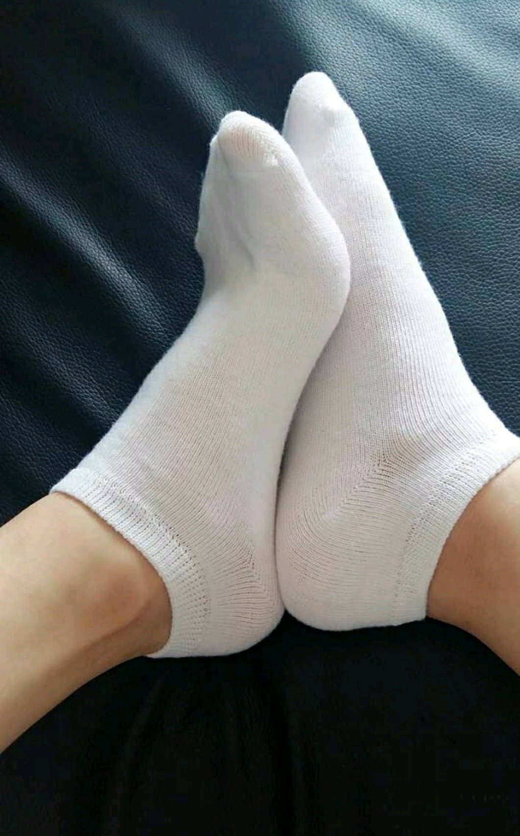 Soft white cotton socks clinging to feet, stretched at the toes with visible fabric texture and warm, personal atmosphere