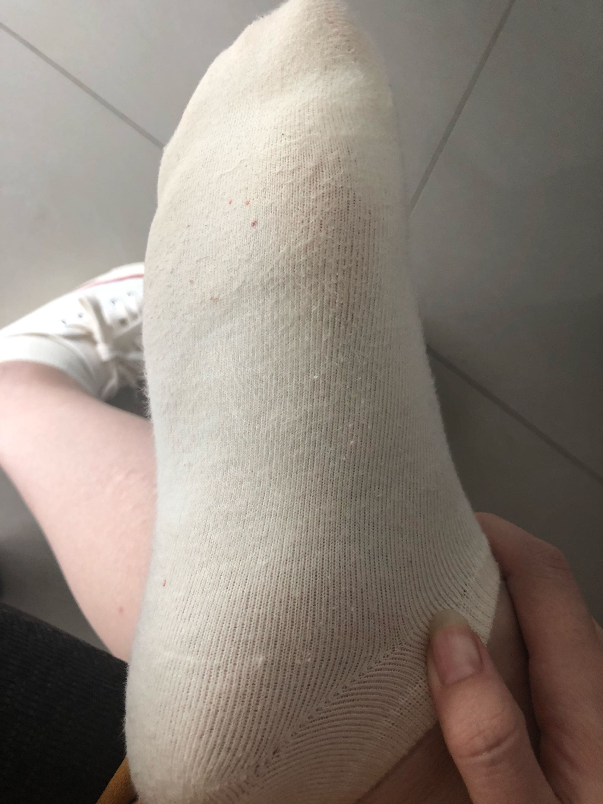 Playful close-up of white cotton socks hugging ankles, slight stretch at the toes, evoking comfort and intimate curiosity