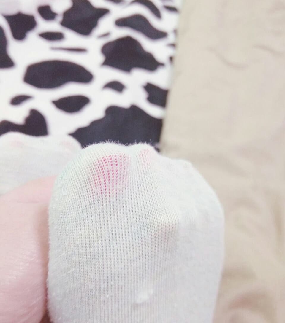 Side view of a foot hovering near a face, sheer stocking glinting under soft studio light