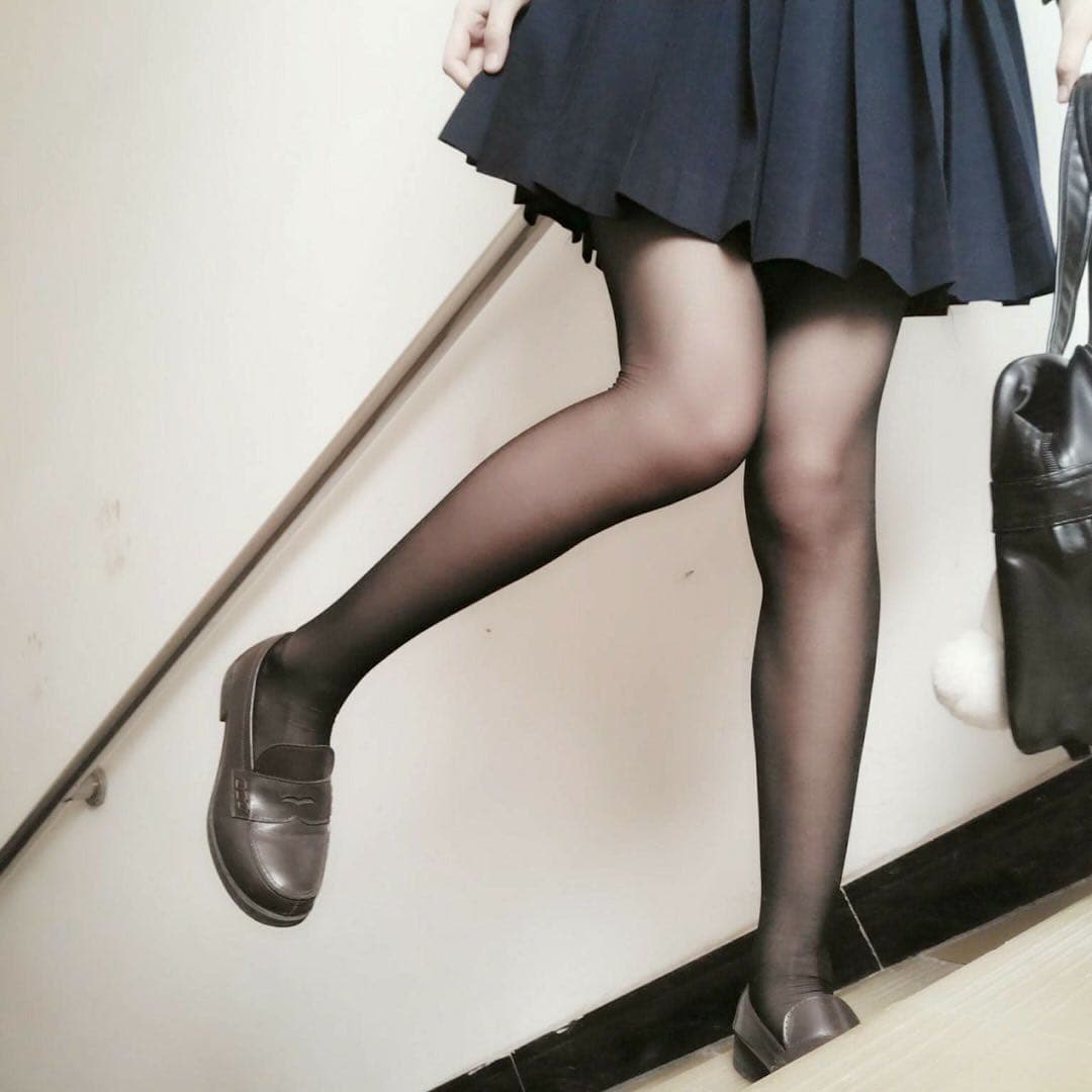 Close-up of bare Asian feet curled on a sofa, delicate ankle and stocking edge visible in warm light