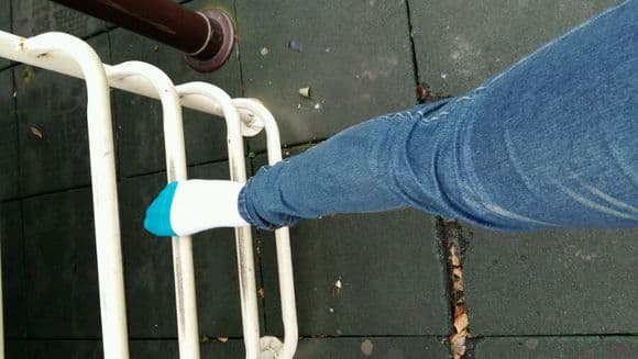 Sunlit feet stretched on grass with cotton socks rolled to ankles, toes splayed toward the sky in relaxed posture