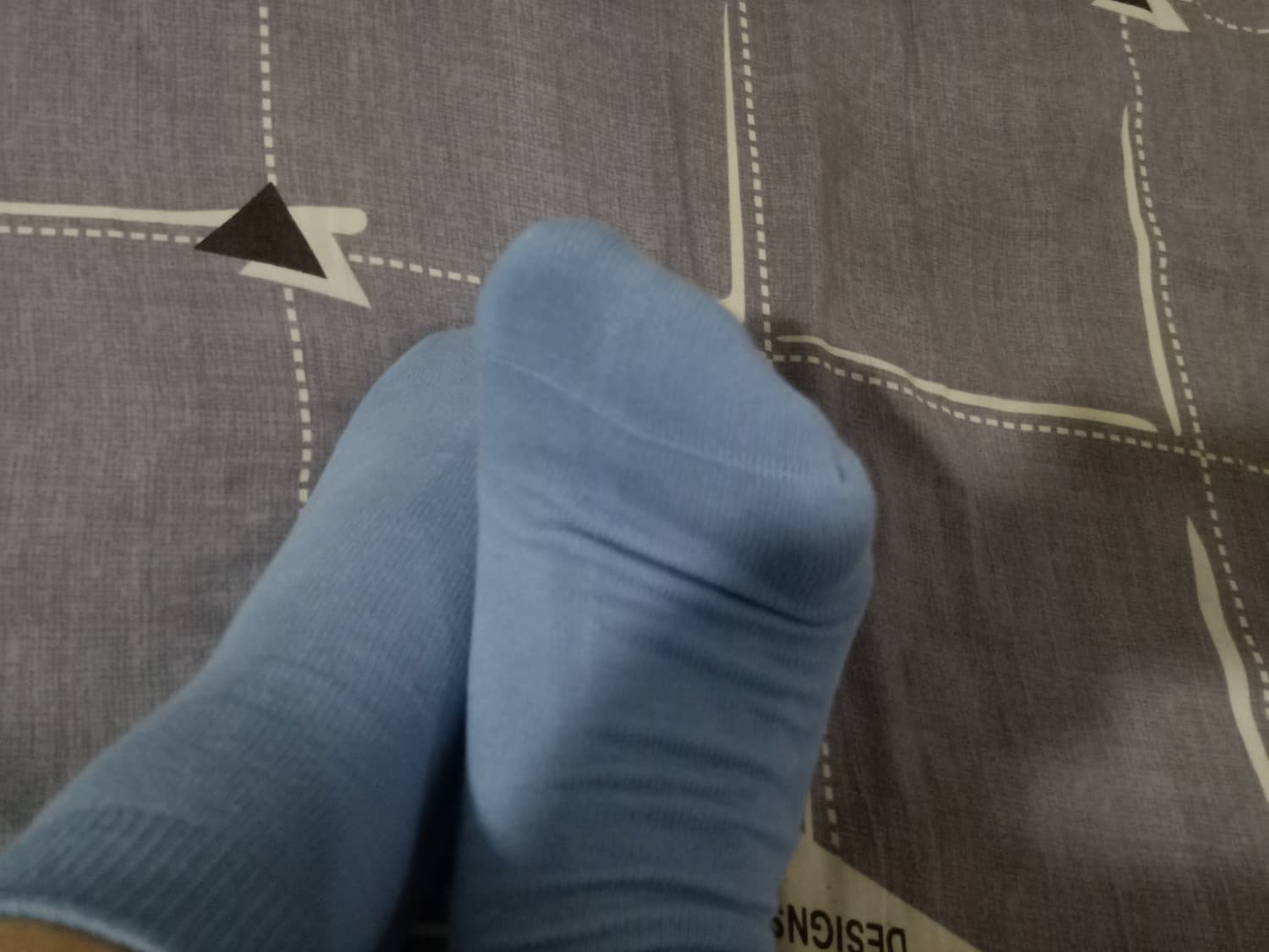 Low-angle close-up of bare feet in sheer nylon, toes peeking from soft cotton socks on a tiled hallway floor