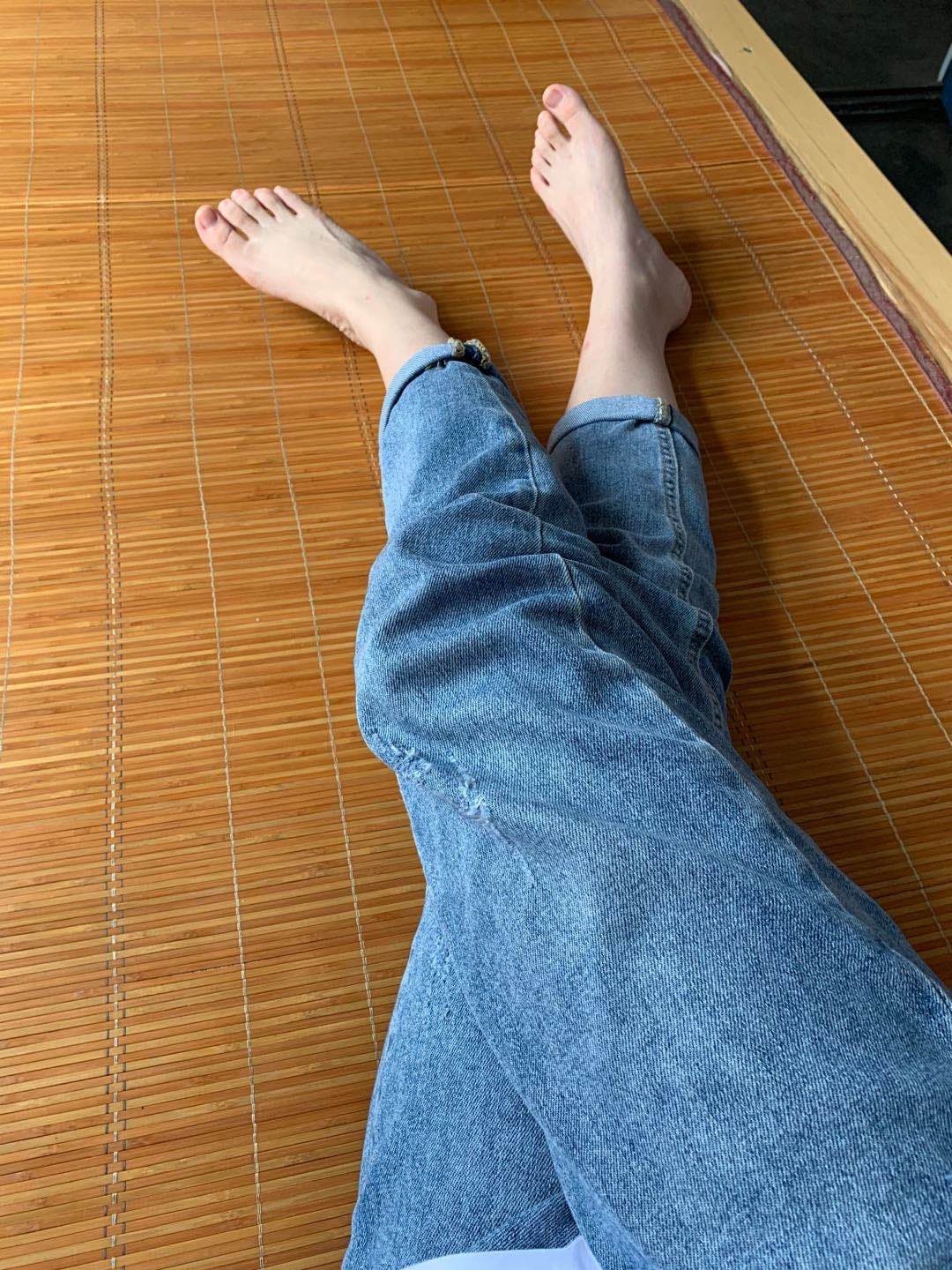 Cropped image of a nurse persona’s feet in sheer pantyhose at a dim karaoke booth, toes relaxed and glossy