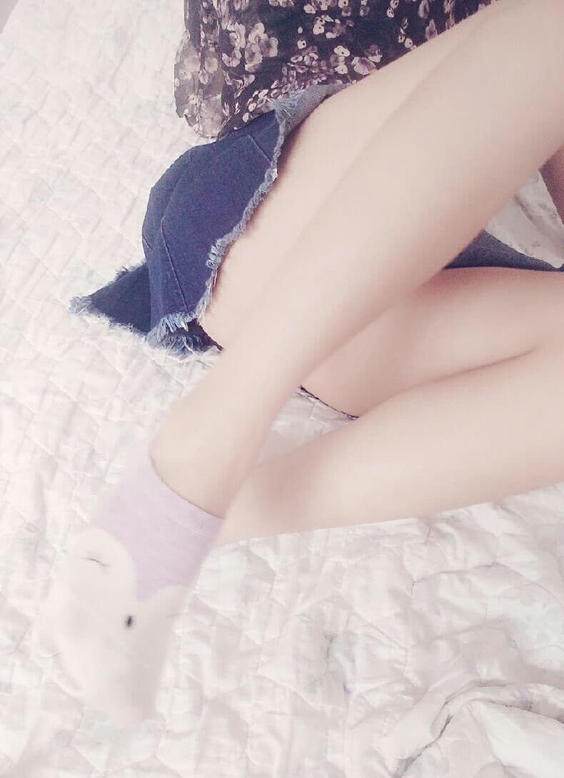 Playful adult in bunny outfit posing with knee-high socks, toes peeking and ankles crossed seductively