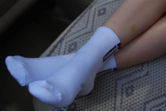 Close-up of worn cotton socks in a car seat, toes gently pressing against soft fabric and crumpled heel