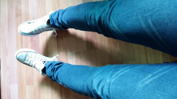 Woman sitting on a bench taking off shoes, stockings wrinkled and bare toes flexing in relief