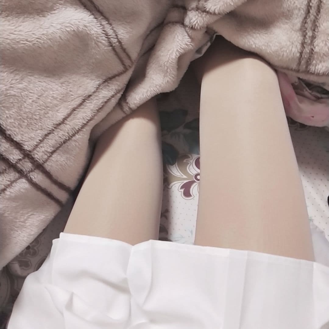 Close-up of bare feet peeking from rolled stockings on a soft bedspread, toes relaxed and arch visible